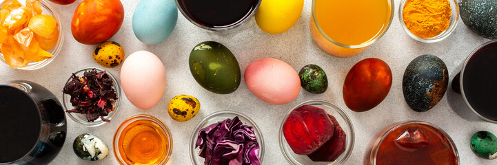 Colorful Easter eggs surround various bowls filled with natural dyes such as beets, turmeric and flower extracts hibiscus, red cabbage and onion peel, showcasing a creative egg decorating process