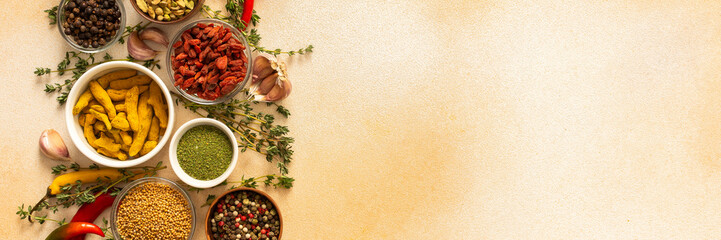 A warm display of spices and herbs on a beige background, each adding rich aromas and flavors,...