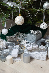 Modern and chic steel-tone gift boxes arranged beneath a beautifully decorated Christmas tree, complemented by candlelight and festive accents for a serene holiday mood