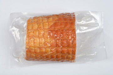 A single, rectangular piece of cooked and smoked ham or meat roll, vacuum-sealed in clear plastic packaging, isolated on a white background