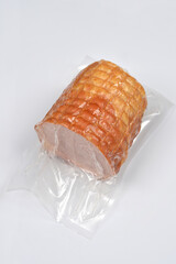 An angled view of a boneless cooked and smoked ham or roll in a clear plastic vacuum pack, isolated on a clean white background