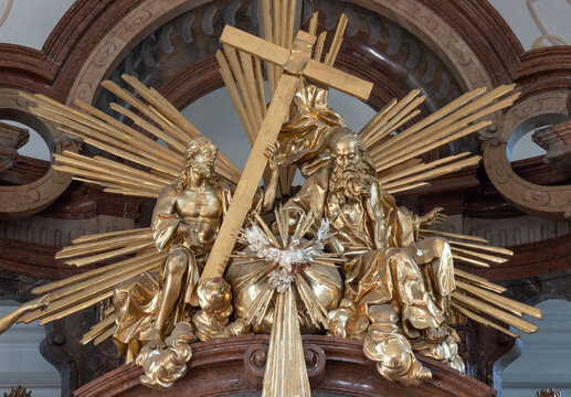 SALZBURG, AUSTRIA - SEPTEMBER 6, 2025: The carved polychrome baroque staue of Holy Trinity on the top of mian altar in the church Pfarrkirche M&uuml;lln by Lorenz Wieser from half of 18. cent. 