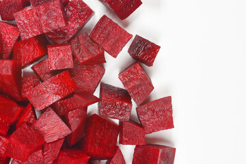 An overhead shot shows a pile of raw, dark red diced beetroot cubes clustered in the lower left corner against a clean, bright white background