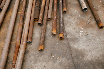 Rusty Metal Pipes Arranged on Concrete Surface