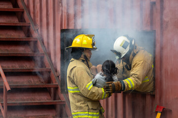 Fototapeta premium Team of firefighter in fireproof clothe are carrying young kid out of the burning building for fire extinguish risk rescue mission and accident management