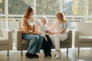 Doctor comforting child and mother in clinic waiting room