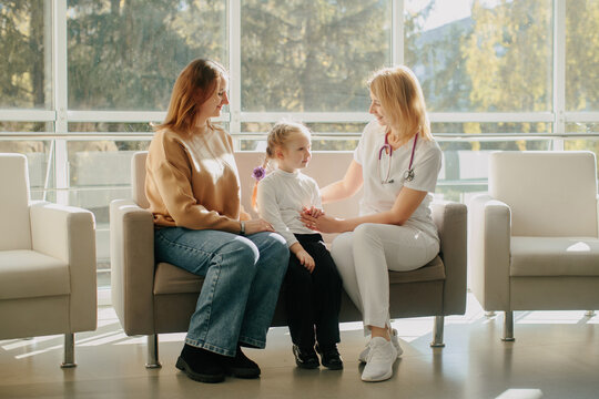 Doctor comforting child patient with mother during clinic visit