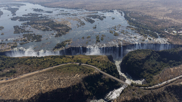 Aerial view of the majestic Victoria Falls plunges into the gorge, creating a misty spectacle amidst the dry landscape, Victoria Falls, Matabeleland North Province, Zimbabwe.