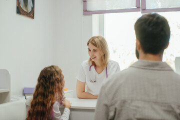Obraz premium Pediatrician consults with young girl and her father in clinic