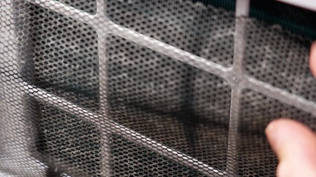 Removing a dusty mesh filter from the air conditioning unit panel. Maintenance of household appliances