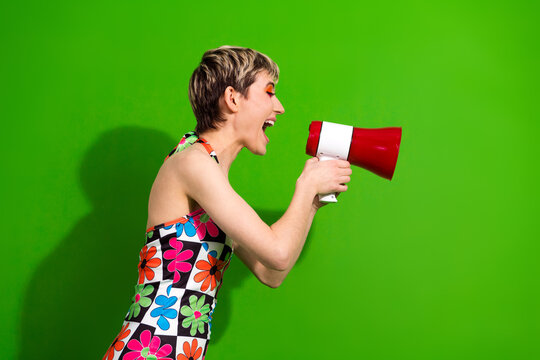 Woman with megaphone in colorful floral dress shouts on green screen for advertising and marketing - Powered by Adobe