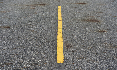 Cracked yellow line on asphalt road surface