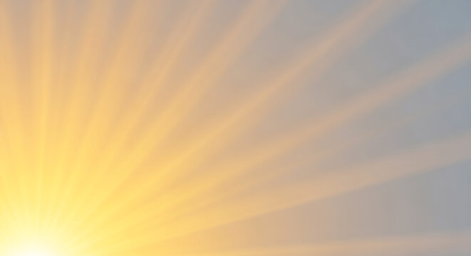Golden sunburst light rays illuminating a hazy sky with soft clouds