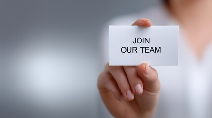 Hand holding a white card displaying join our team, signifying recruitment, hiring, and seeking new talent for career development and business growth within human resources with copy space