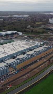 Vertical format sideways drone pan over the rear of the Google Data Centre in Waltham Cross, Hertfordshire. Captures the full scale of the facility, surrounding greenery, and infrastructure.