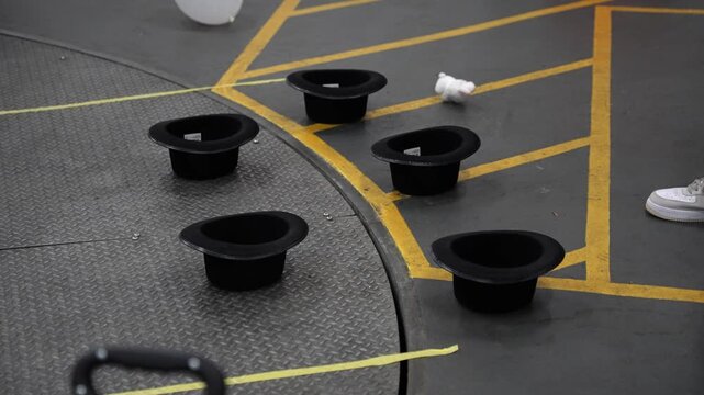 Close up of people thowing toy bunny rabbits into magician hats upside down and missing but bouncing in slow motion on the floor.