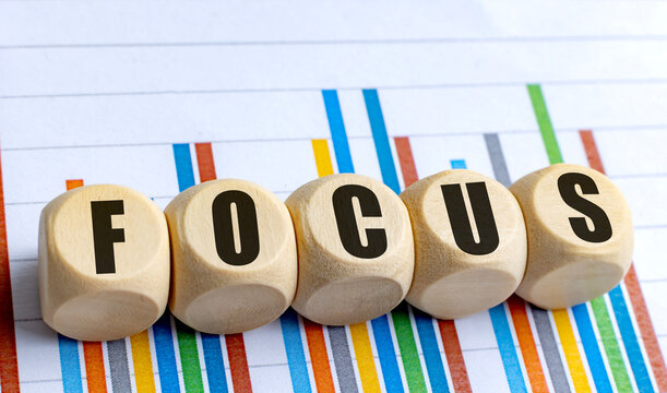 Wooden cubes with word focus on colorful bar chart background representing business concentration