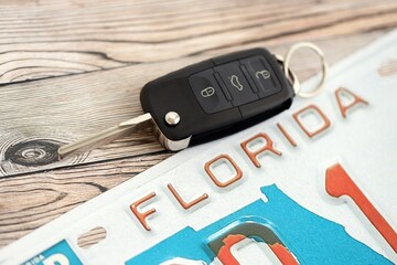 Remote control car keys on Florida license plate on wooden background. Concept of driving in Florida. Reaching a driving permit