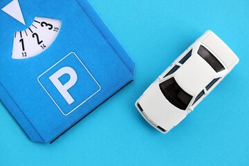 Fototapeta premium Parking disc for windshield and white toy car. Limited time parking system in european countries. Concept of parking time count in busy parking lots