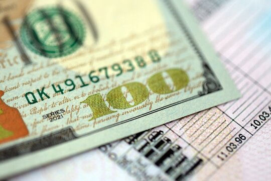 Hundred dollar bill on US driver license close up. Concept of driving lessons or automobile taxpaying