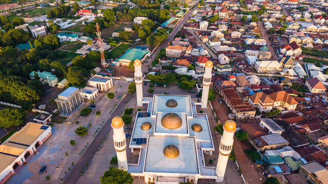 Aerial view of a grand mosque with towering minarets amidst a sprawling cityscape bathed in the warm glow of the setting sun, Ungwan Sarki, Kaduna, Nigeria.