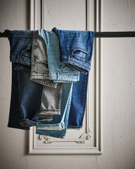 A stylish display of various washed denim jeans hanging on a metal grid rack, showcasing different textures, colors, and modern casual fashion details.