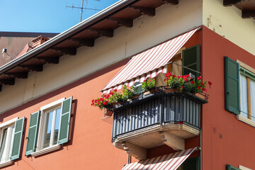 Cozy balcony in an Italian town with warm architecture and charming details. Peaceful Mediterranean atmosphere, flowers, sunlight, and traditional building style