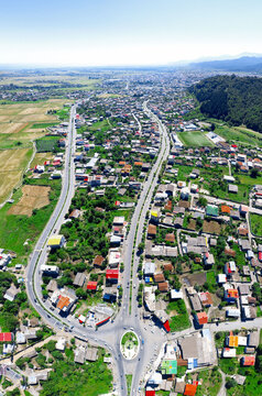 Aerial view of Azadi Square, a vibrant roundabout amidst the buildings and greenery, a pathway to the distant horizon, Hashtpar, Gilan Province, Iran.