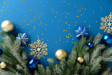 Christmas decorations with frosted fir branch and gold snowflake on blue background