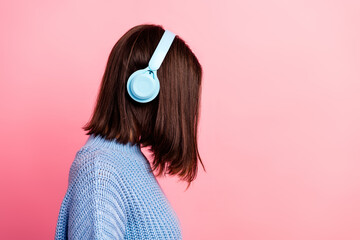 Young woman with blue headphones wearing a knit sweater posed against pink background conveying music fashion and lifestyle vibe for stylish casual branding and lifestyle content
