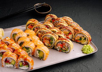 Elegant sushi platter with assorted rolls and sauces on dark background