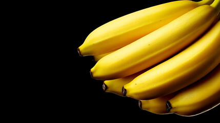 A close up shot of a bunch of ripe yellow bananas against a stark black background in a studio setting christmas and happy new year background 