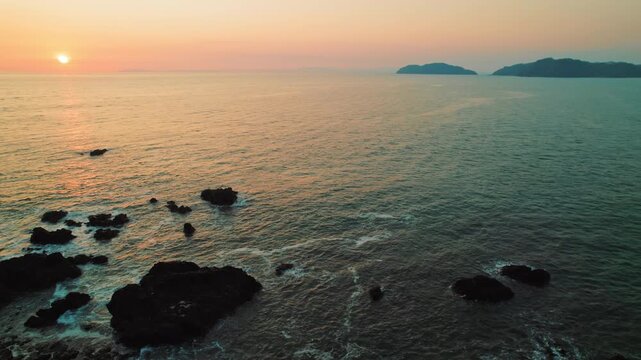 Golden sunset over Pacific Ocean with rocky formations in Costa Rican
