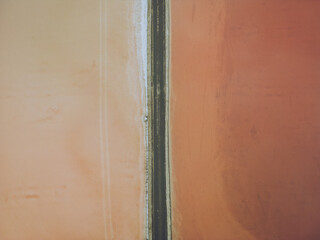 Aerial view of pink and red salt marshes divided by a narrow strip of land, Bacuta Salt Marshes, Huelva, Andalucía, Spain.