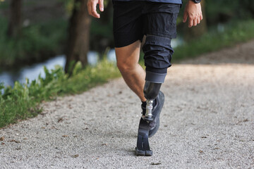 Man with a disability, using a versatile prosthetic leg, walking along the greenway during daily recreation and relaxation activities.