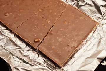 Close-up of a milk chocolate bar with nuts in foil