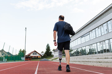 Obraz premium Athlete with a prosthetic leg trains on an outdoor track under a clear sky, focused on exercise.