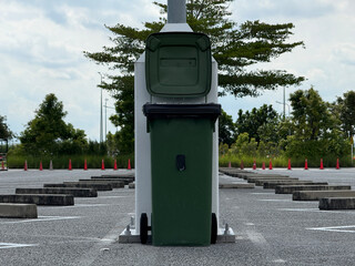 Green trash bin placed at parking lot with traffic cones