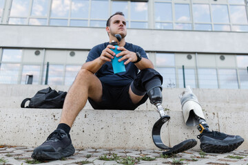 Athlete with leg amputation resting on outdoor steps after workout. Strength, motivation, and healthy living concepts.