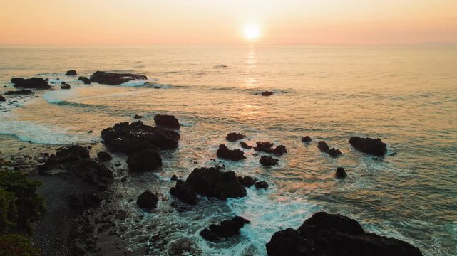 Rocky coastline of Jaco beach illuminated by warm golden sunset light Costa Rica