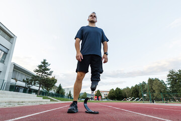 Man with a disability running on the athletic track wearing a prosthetic leg, blade with a heel plate designed for sports activities.
