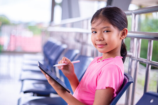 Smiling Young Girl Using Stylus on Digital Tablet in Modern