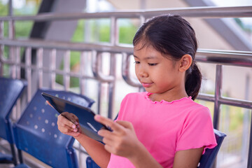 Young Girl Using Tablet While Sitting in Public Waiting Area