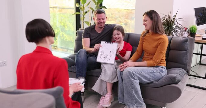 Caucasian family art therapy with asian facilitator showing child drawing on paper, parents smile and encourage, cozy living room