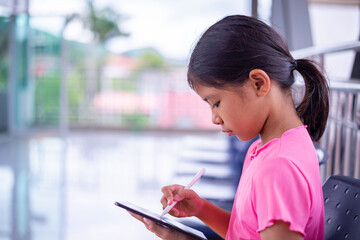 Focused Young Girl Using Stylus on Digital Tablet in Modern Public Space