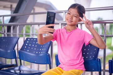 AHappy Girl Taking a Selfie with Smartphone While Sitting Outdoors