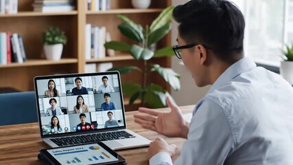 Asian businessman in glasses participates in a virtual team meeting from his home office, discussing business reports and financial charts with colleagues online. - Powered by Adobe