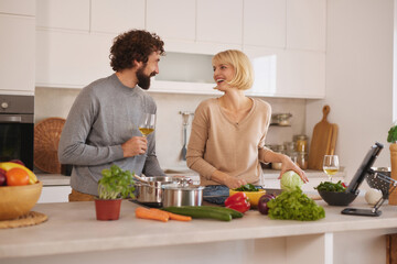 In a stylish kitchen, a man and a woman happily cook together, laughing and enjoying each other's company while preparing a meal with fresh ingredients.