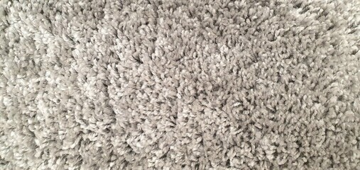 Fluffy carpet texture background. Soft rug for a bathroom or bedroom. Beige or gray fluffy carpet texture. Home interior decor. Terry rug.
