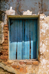 Wooden blue window and wall of an old, abandoned house, destroyed by time